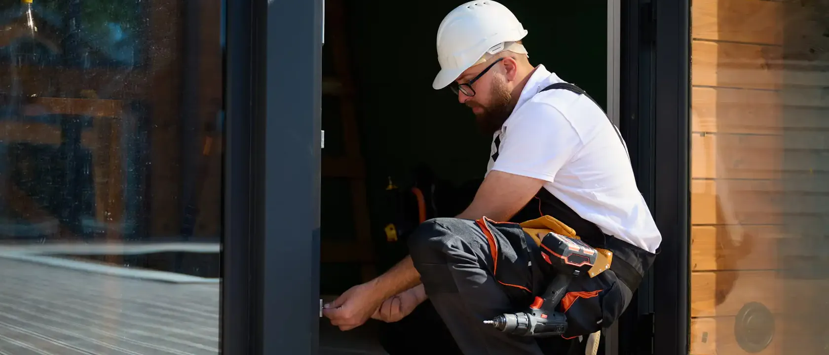 Technician adjusting hardware at the base of an aluminum-framed commercial door